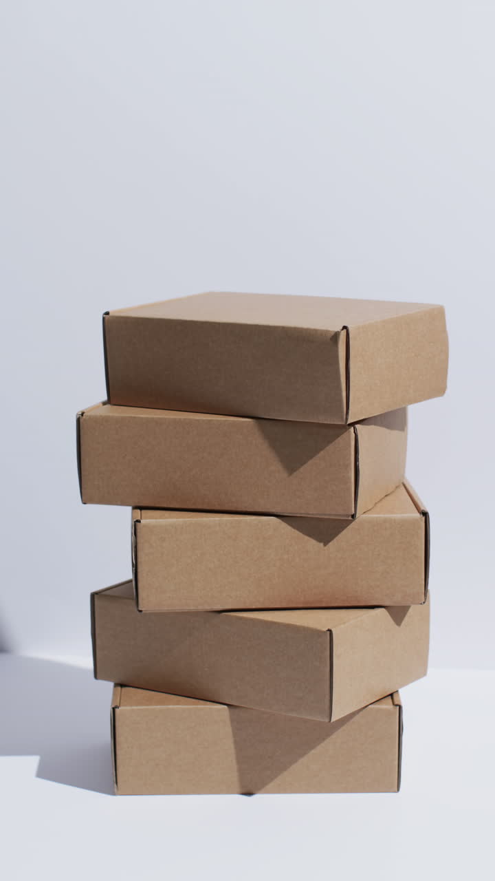 Vertical video of stacked cardboard boxes with copy space over white background
