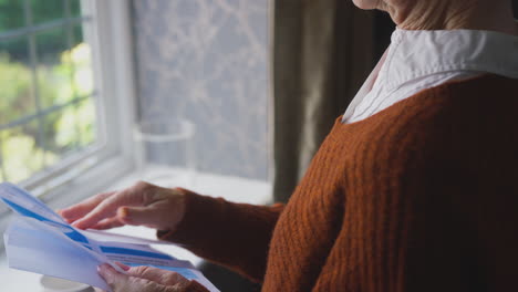 close up of senior woman opening uk energy bill concerned about cost of living energy crisis