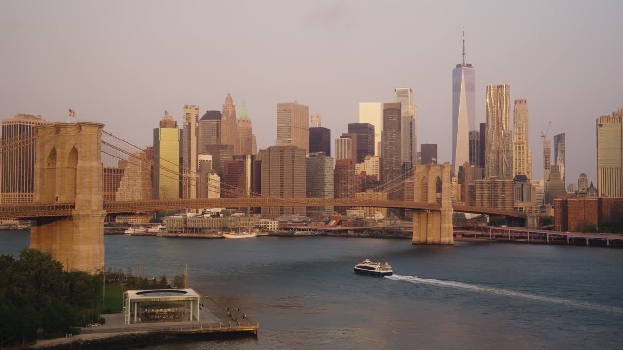Boat on East River below Brooklyn in ridge with skyline in backdrop at sunset - NYC, America