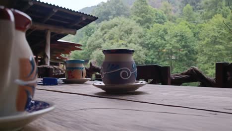 ceramic cups on a rustic table with a peaceful forest view in the background