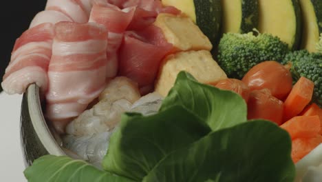 close up of a pot of shabu ingredients spinning around on white table in the black background kitchen