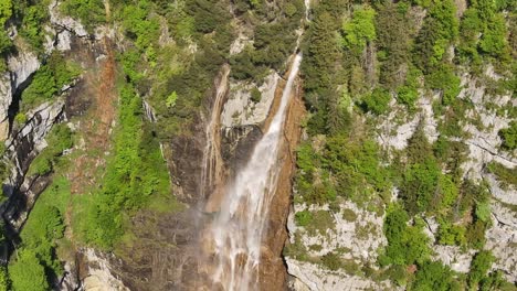 seerenbachfälle waterfall cascading from rocky cliffs into lush forest in betlis, switzerland drone view