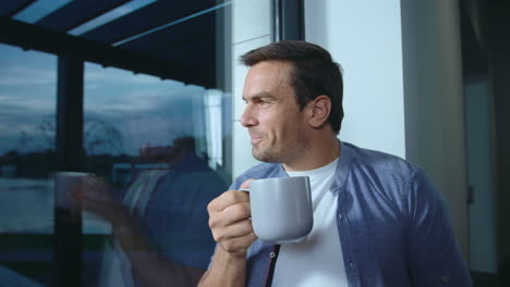 happy man staying near window after working day. relaxed man having rest.