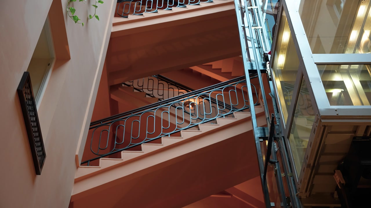 Step into a timeless journey through a vintage spiral staircase enveloped by ambient lighting. The intricate wrought iron railings add elegance while the warm tones create a nostalgic atmosphere.