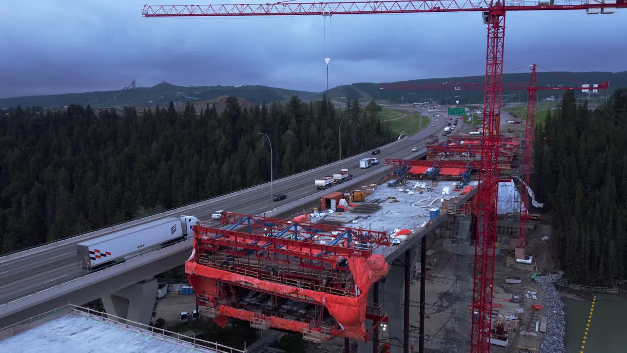 Crane workers on bridge construction by highway bridge tilt and pan