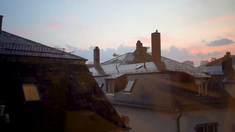 twilight over wet rooftops with heavy rain, serene urban landscape, warm tones at sunset