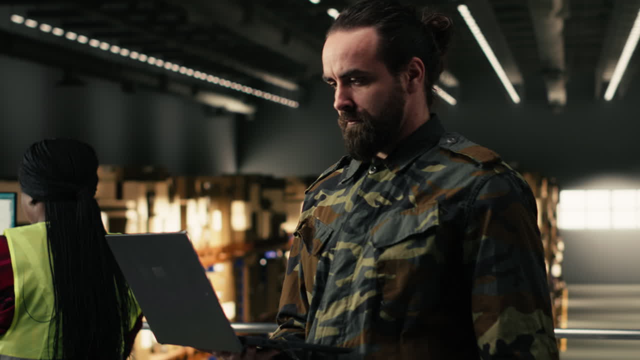 Menedżer logistyki pracujący na laptopie w magazynie przemysłowym.