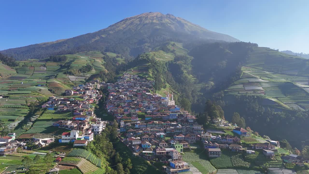 Drone shot showing peaceful mountain settlement with layered terraced fields and traditional homes in slightly foggy morning. Nepal Van Java, Indonesia