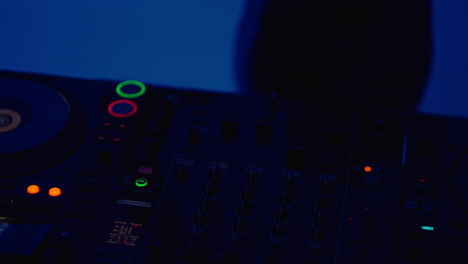 a female dj playing music on a dark stage