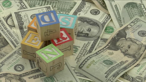 wooden alphabet blocks sit on top of a pile of money