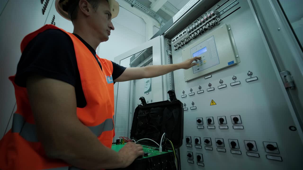 el ingeniero eléctrico que trabaja comprueba la tensión de corriente eléctrica y la sobrecarga en la parte delantera del gabinete del centro de carga o de la unidad de consumo para el mantenimiento en la sala principal del sistema de distribución de energía.