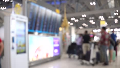 blurred footage of passengers looking at arrival departure board and walking in the international airport terminal. 4k video with defocused effect.