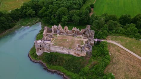 high-angle drone shot showing the inner courtyard of guildo castle ruins, with surrounding forest and estuary in brittany, france
