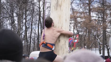 Man Climbing a Log During a Russian Festival