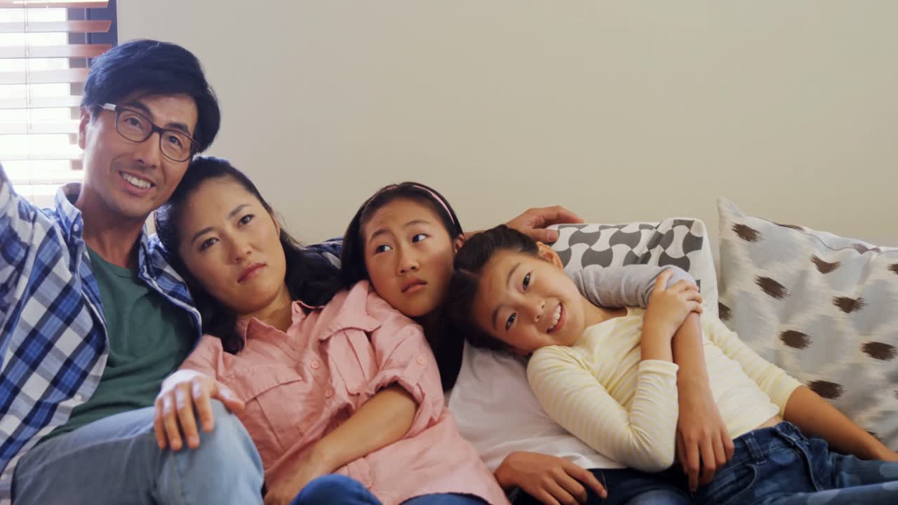 웃는 가족이 거실 4k의 소파에서 휴식을 취하고 있습니다.