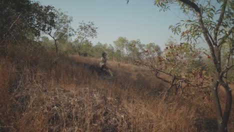 Ethereal-establishing-shot-of-young,-beautiful-Indian-woman-sitting-in-a-field-of-tall-dead-yellow-grass