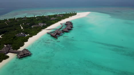 wide lowering drone shot of private villas over the turquoise water