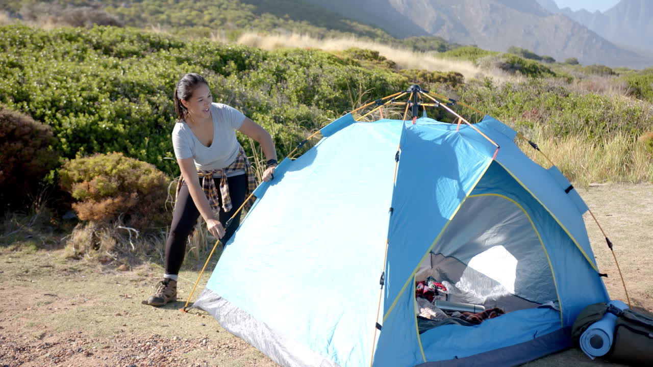 Setting up tent, woman preparing campsite during mountain hike adventure