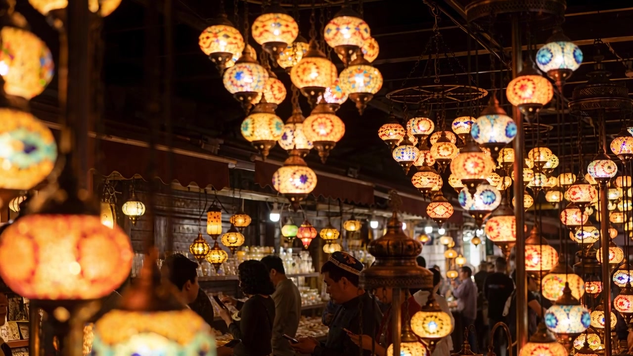 Pulling back camera, revealing colorful mosaic lamps and shoppers browsing at night market