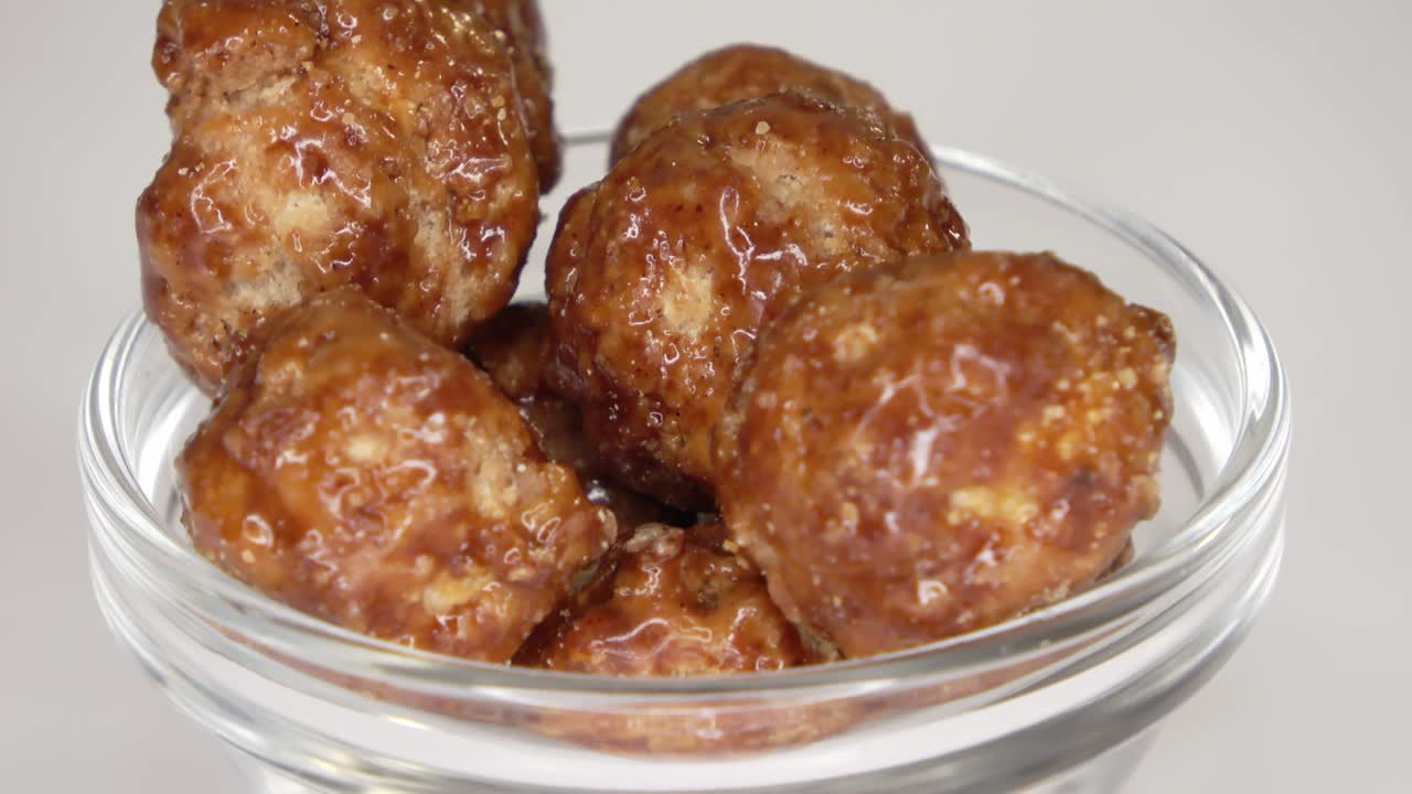 색 배경에 작은 그에서 회전하는 많은 캔디 매카다미아 견과류의 루프 가능한 영상입니다.