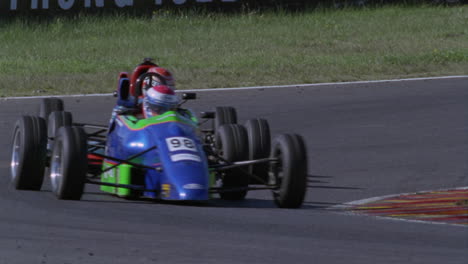 three racing cars race around a track