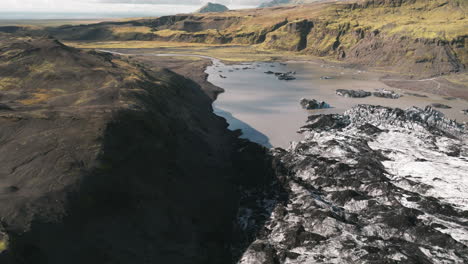 right to left aerial sliding shot of receding iceland glacier, silty pond