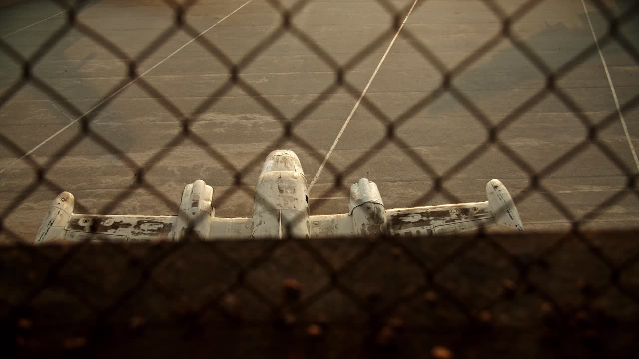 замедленная съемка сверху половины самолета на земле за сеткой из колючей проволоки, старый заброшенный самолет кинематографический кадр создания, афинский аэропорт эллинико одиночество