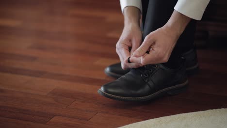 groom putting his wedding shoes on wedding day. hands of wedding groom