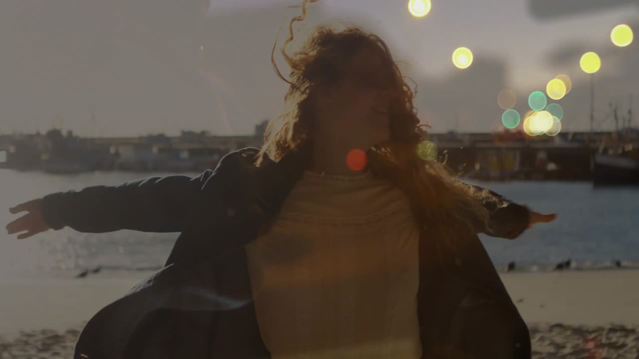 Kvinna snurrar på stranden, vinden får henne att snurra, armarna öppna, filmar reklam med animerad ljusreflex som speglar snurren