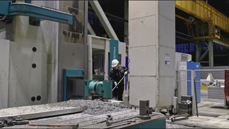 factory worker clearing metal shavings from a cnc machine