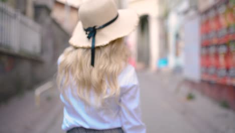 slow motion:attractive young beautiful girl with hat walks and discovers places in narrow street