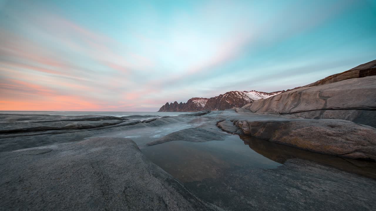 Snowy mountains and rocky coastline at Tungeneset, Senja, captured in a serene timelapse