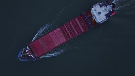 The-Rix-Union-Cargo-Vessel-Leaves-Behind-a-Frothy-White-Trail-as-it-Travels-Along-the-River-in-Zwijndrecht,-Netherlands---Aerial-Topdown-Shot