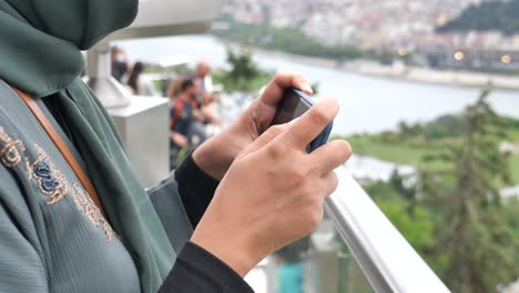 woman in hijab taking a picture of a cityscape