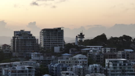 Drohnenflug-über-Luxusapartments-Am-Meer-Und-Leuchtturm-Bei-Sonnenuntergang,-Teleparallaxe-Australien