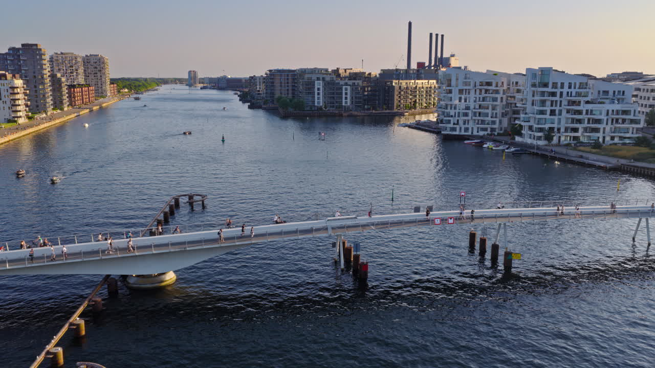 Aerial drone view of the Lille Langebro pedestrian bridge with people cycling and walking across the harbour at sunset in Copenhagen, Denmark