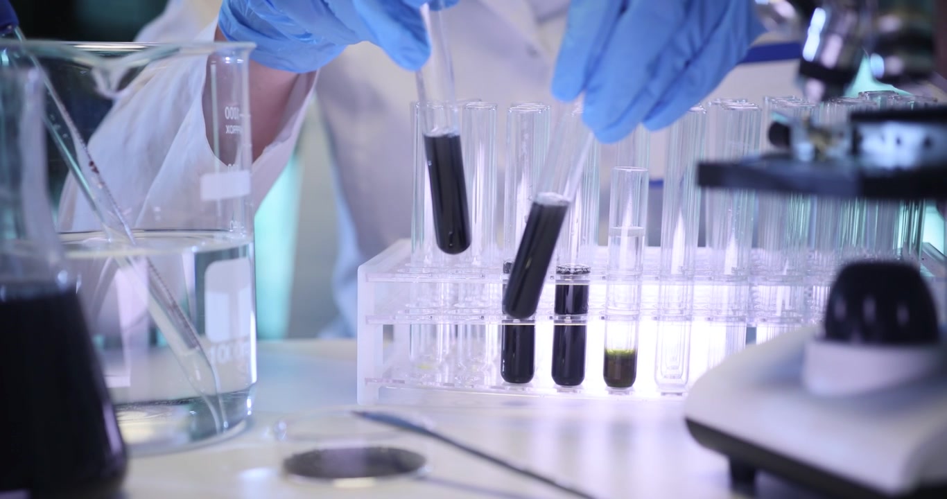 Una scienziata prende delle provette con liquido scuro dalla rastrelliera