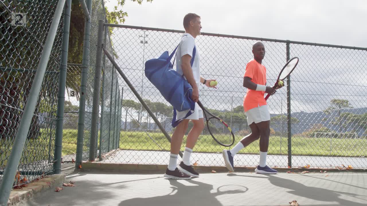 vista trasera de diversos jugadores de tenis masculinos caminando y hablando en la cancha al aire libre en cámara lenta