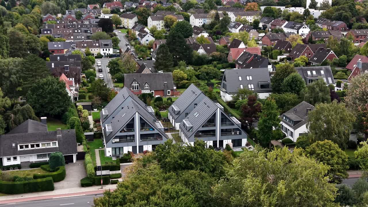 Luxury villa apartments with grey roof and balcony in German town. Cloudy fall day in neighborhood. Aerial orbit shot. Cars ok street with green trees