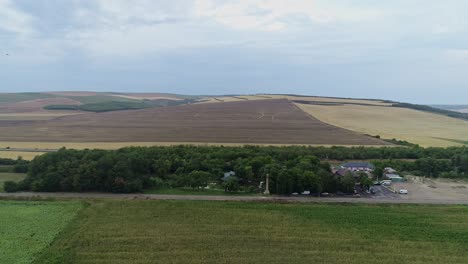 Drohnenansicht-Einer-Ländlichen-Gemeinde,-Umgeben-Von-Ackerland-Und-Hügeln