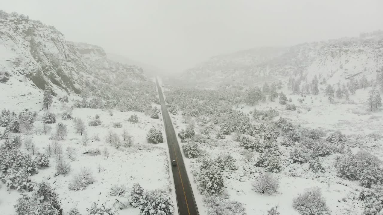 Aerial push in shot of a fresh snowfall blanketing the landscape around the main road at the top of Zion National Park.