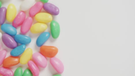 video of close up of multi coloured sweets with copy space over white background