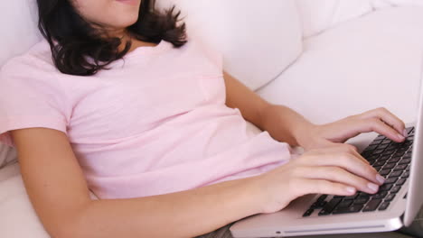 Woman-sitting-on-a-sofa-using-her-laptop