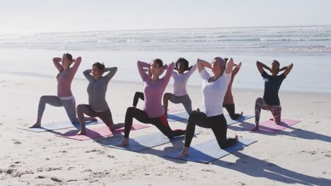 Multi-ethnic-group-of-women-doing-yoga-position-on-the-beach-and-blue-sky-background