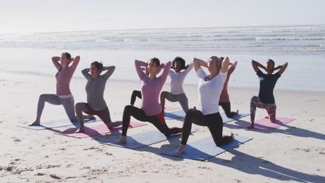 Multiethnische-Gruppe-Von-Frauen,-Die-Yoga-Position-Am-Strand-Und-Im-Hintergrund-Des-Blauen-Himmels-Machen