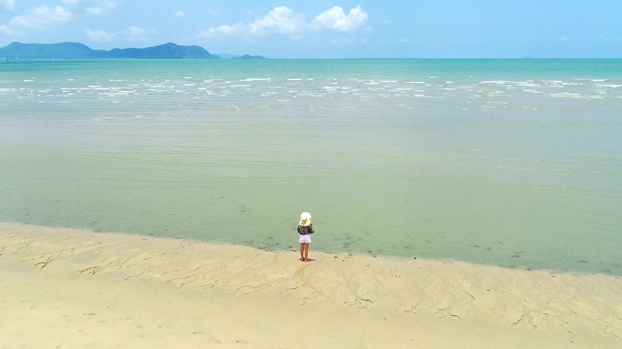 4K woman walk on the beach, foot print on sand texture and coconut tree on the beach photo by drone.