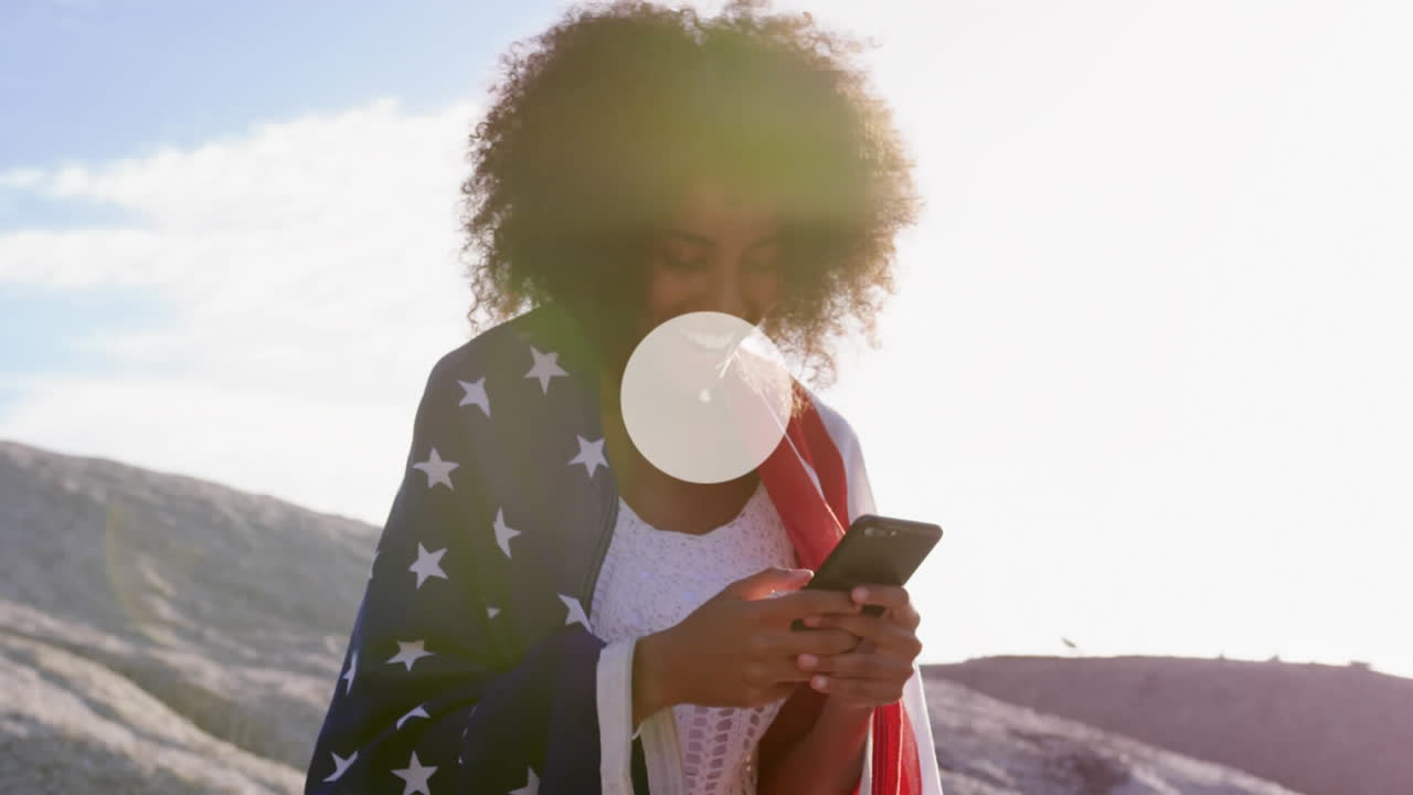 red de iconos digitales contra mujer afroamericana envuelta en bandera estadounidense usando un teléfono inteligente