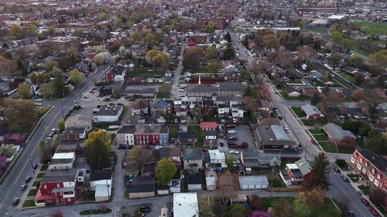 Ampia veduta aerea di una città americana al tramonto con case residenziali, strade e alberi. Vita suburbana tranquilla e luce serale soffusa in un quartiere silenzioso in un suggestivo scenario statunitense. Inquadratura laterale
