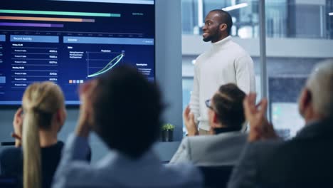 presentation event: black businesswoman talks of e-commerce product sales showing tv big data statistics, charts, revenue growth infographics. press conference for digital entrepreneurs, investors