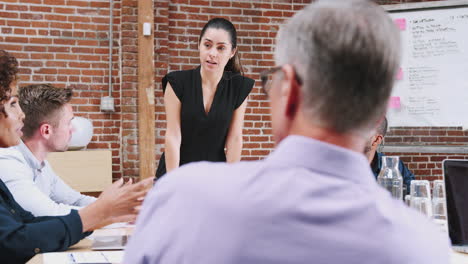 Junge-Geschäftsfrau-Steht-Und-Leitet-Bürobesprechung-Am-Tisch